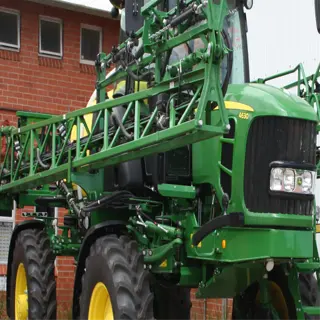 green agricultural sprayer with large wheels and boom arms