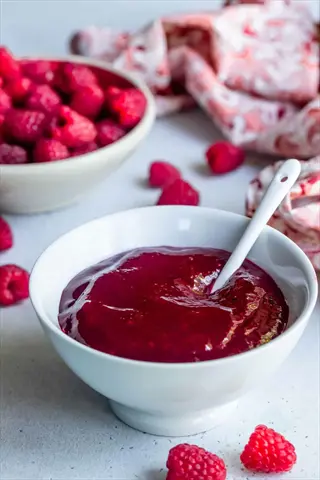 homemade raspberry sauce with fresh berries - the result of effective seasonal raspberry care and harvest utilization