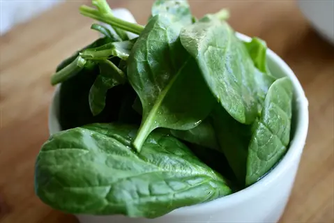 large lettuce leaf and basil-like fresh greens in a white bowl