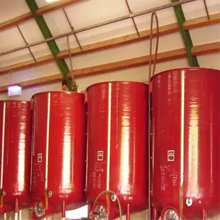 large red fermentation tanks lined up in a warehouse setting