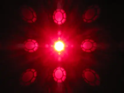 led optical lens effect showing bright central light with radiating red patterned glow from lens system