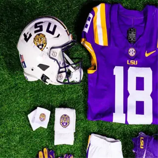 lsu football uniform with purple jersey, helmet, and accessories on grass