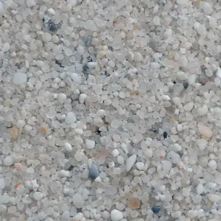 macro photograph of coarse construction sand showing light beige, gray and subtle orange mineral grains