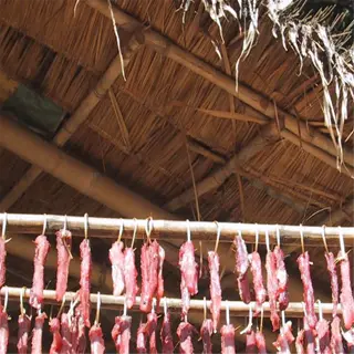 meat strips hanging under a thatched roof for sun-drying