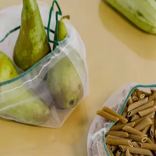 mesh produce storage bags containing pears and pasta, with zucchini in the background
