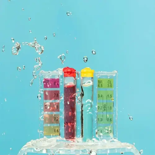 ph testing kit closeup showing color-coded liquid vials and reference chart with water droplets against blue background