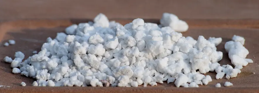 pile of white perlite horticulture granules for soil aeration on brown surface