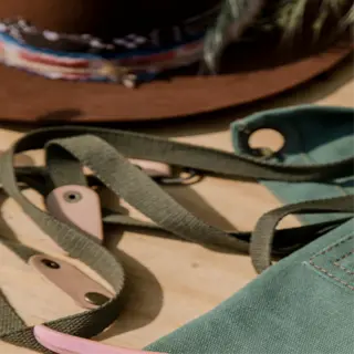 pink root pruning shears on a green apron with a hat in the background