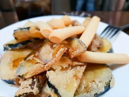 plate of crispy fried eggplant slices (prepared from frozen) served with breadsticks, demonstrating use of frozen eggplant in cooking