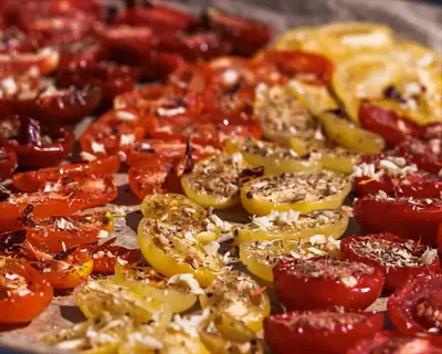 roasted cherry tomatoes confit with herbs and garlic, featuring mixed varieties like yellow pear in red, yellow, and orange on a baking sheet