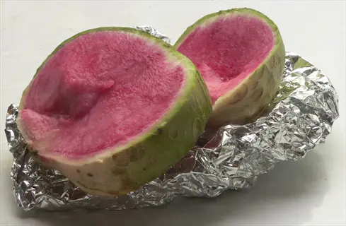 sliced watermelon radish showing vibrant pink interior and green skin on aluminum foil