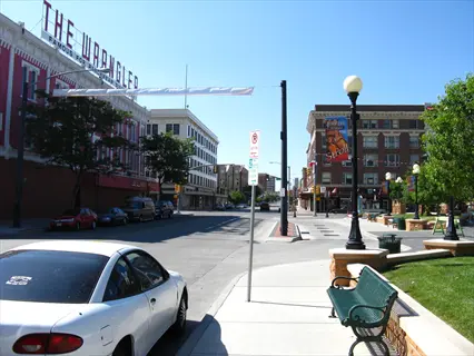 sunny street view in cheyenne featuring historic brick buildings, parked car, and green bench with vintage street lamps