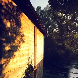 sunset lighting on wooden building by river, sunlight management