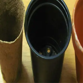 three different types of planting pots: a peat pot, a black plastic pot, and a terracotta pot