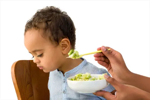 toddler in high chair during mealtime - feeding and location context with broccoli