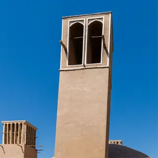 traditional iranian architecture featuring humidity domes and wind towers against a clear blue sky