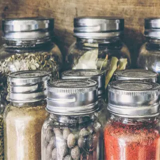 various spices in glass containers on a wooden shelf