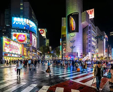 vibrant tokyo cross scene at night with crowded pedestrian walkway, glowing neon signs, and wet streets reflecting bright city lights