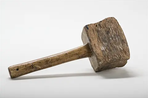 vintage wooden mallet tool with weathered head and handle on plain background
